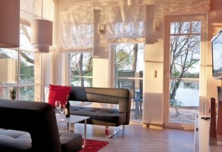 Wohnbereich der Ferienwohnung Fischadler mit großen Scheunenfenstern // © Andre Pretzel Wohnbereich der Ferienwohnung Fischadler mit großen Scheunenfenstern // © Andre Pretzel