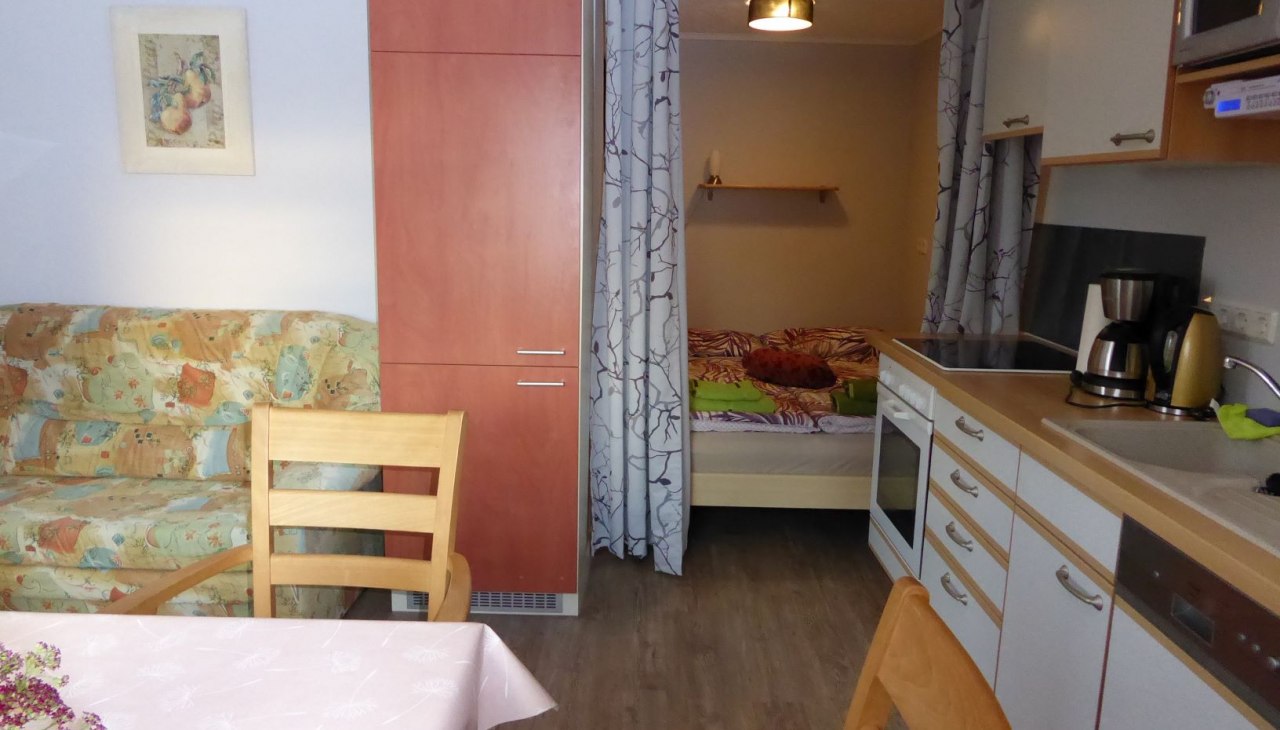 Kuchnia-pokój dzienny z wnęką sypialną, stołem, kanapą, © Beate Lindstaedt