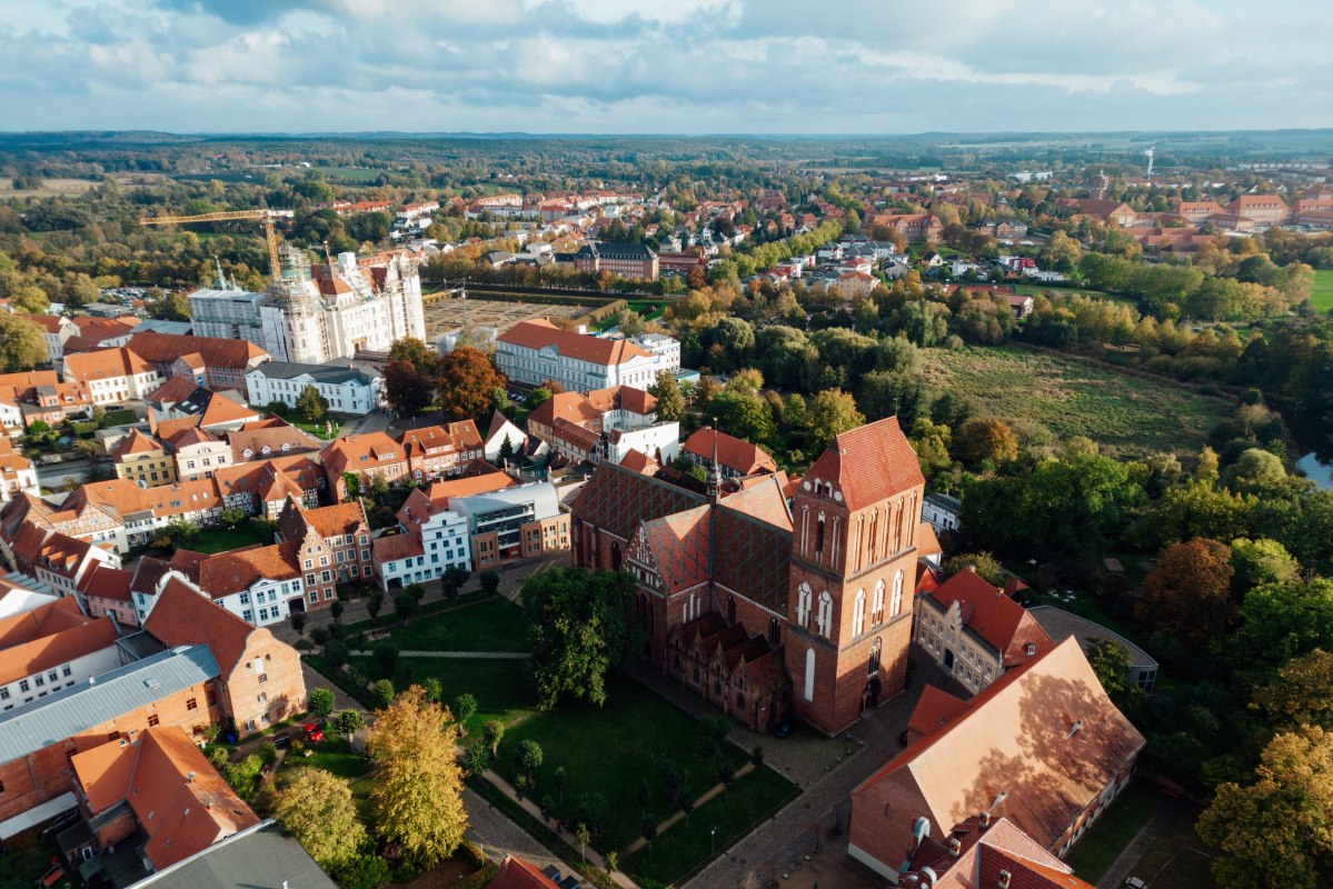 Brick architecture meets Renaissance splendor: G&uuml;strow Castle and the cathedral dominate the historic old town. A bird's eye view of Mecklenburg's centuries-old architecture can be seen between autumn-colored trees and red roofs. A stroll through the alleyways leads to hidden squares and architectural treasures. // &copy; MV-T/Petermann