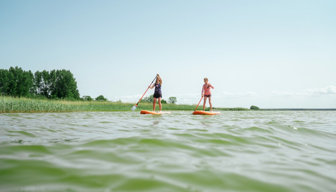 Een moeder peddelt met haar dochter op stand-up paddle boards op de Bodden bij Born aan de Darß