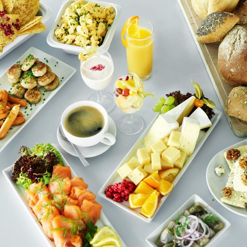 Varied breakfast buffet with cheese, salmon, bread, fruit, yogurt, scrambled eggs and coffee on board a ferry.