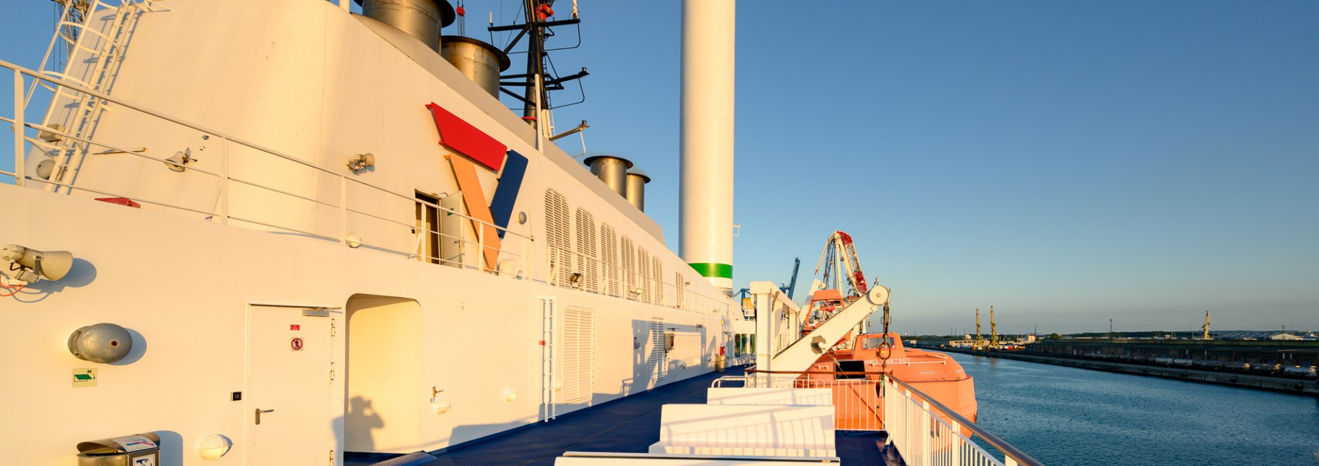 Benches and technology on the upper deck of the Scandlines ferry in the evening light with a view of the harbor.