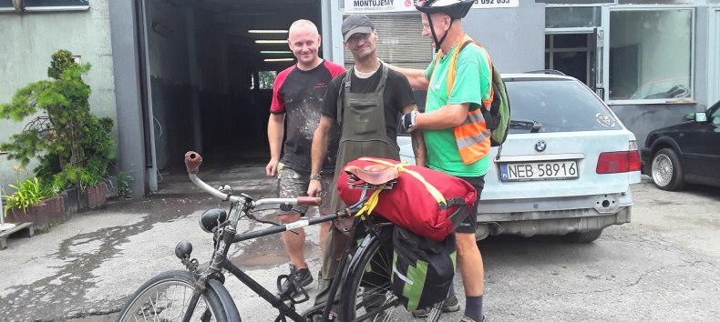 In the foreground a bicycle with red luggage, behind it Reinhard Klette with two Polish citizens. // &copy; Reinhard Klette
