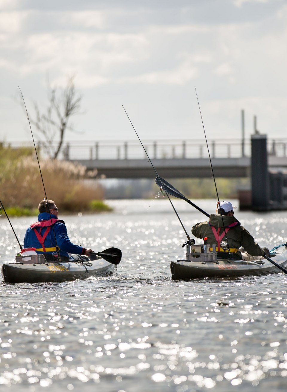 Two anglers paddle down the Peene in their kayaks while their rods are ready for the next catch. The peaceful atmosphere on the water and the glistening sunrays create the perfect backdrop for a relaxed fishing trip., © TMV/Laeufer Two anglers paddle down the Peene in their kayaks while their rods are ready for the next catch. The peaceful atmosphere on the water and the glistening sunrays create the perfect backdrop for a relaxed fishing trip.