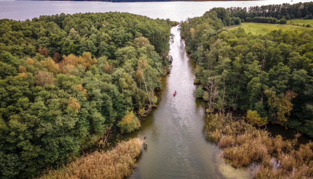 Een kano peddelt door een klein kanaal van het ene meer naar het andere.