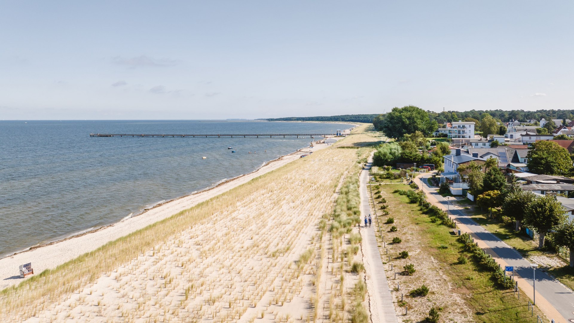 Rozległa piaszczysta plaża w Lubminie z wydmami, promenadą i spokojnym Morzem Bałtyckim w słońcu Zatoki Greifswaldzkiej.