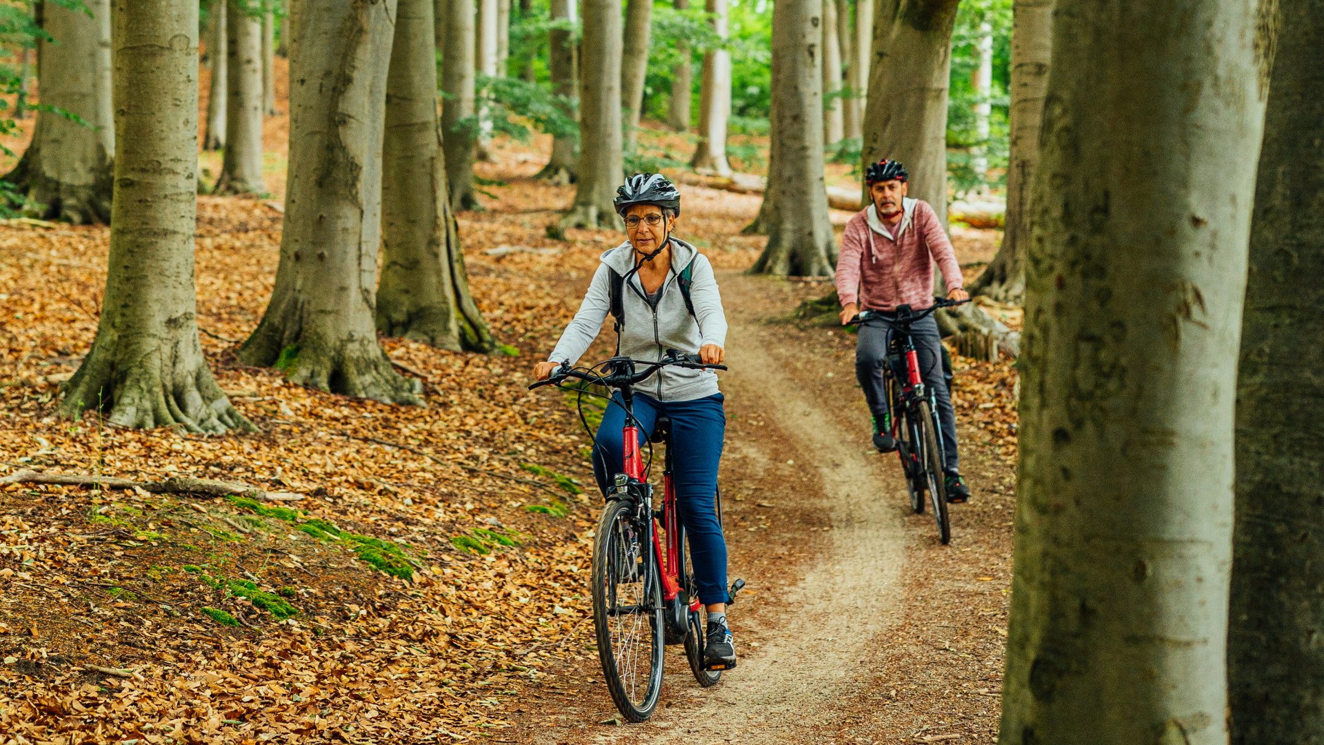 Een stel rijdt op e-bikes door het bos over bospaden