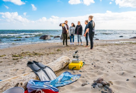 Z wakacyjnymi strażnikami na plaży w Göhren - dzieci stoją na plaży ze strażnikiem i zwiedzają.