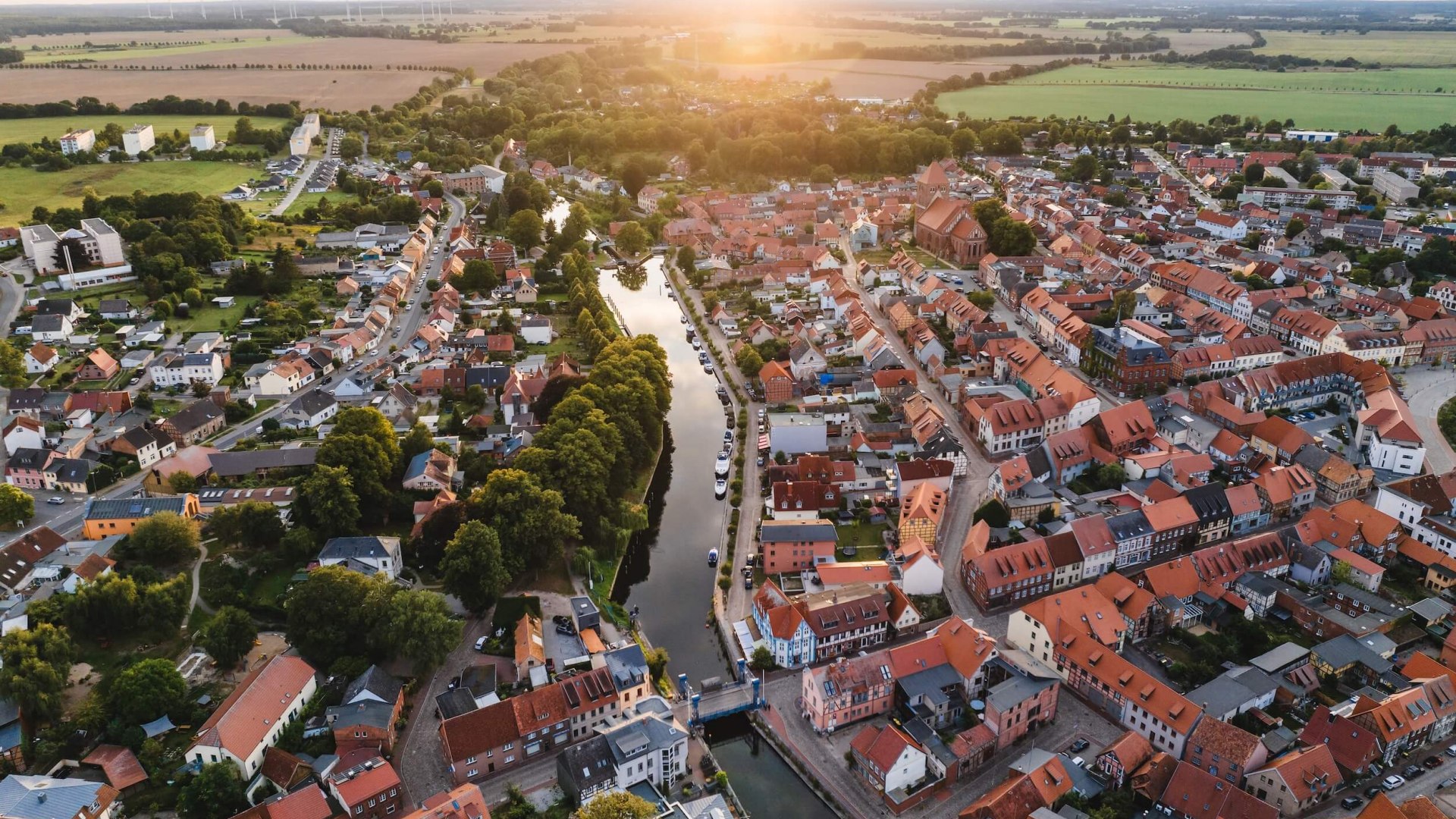 Widok z lotu ptaka na miasto Plau am See o zachodzie słońca. W centrum widoczny jest most windowy.