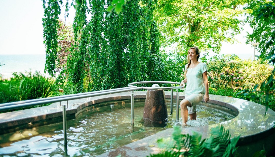 A woman walks around in a Kneipp water basin.