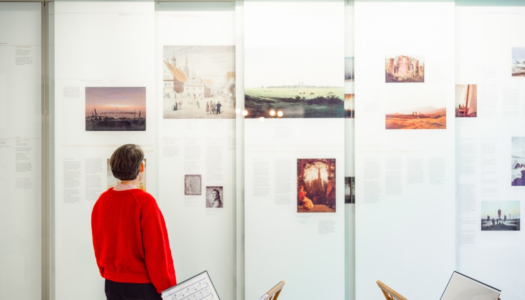 Visitor looking at Caspar David Friedrich reproductions in the exhibition room in Greifswald.