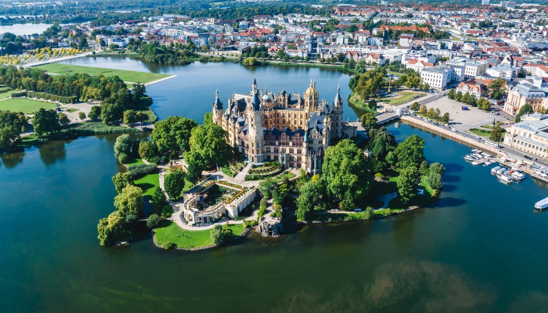 Schwerin Castle from the air in summer. The castle stands on a small island surrounded by water.