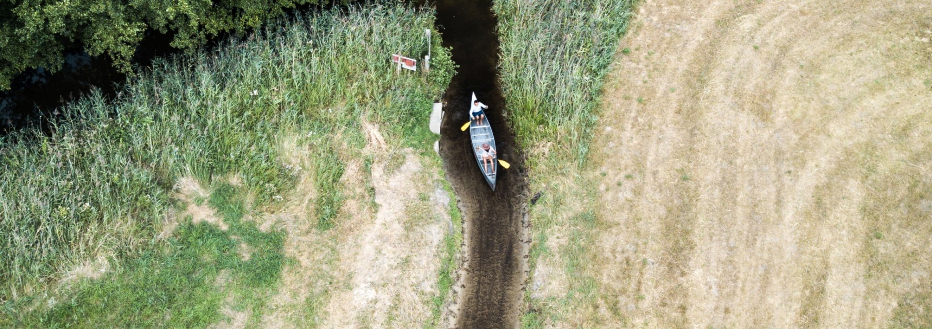A canoe on a canal that has almost no water left from the air.