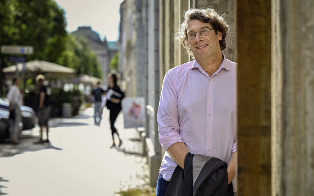 De auteur Ralf Günther draagt een roze shirt en leunt tegen een huismuur in een stadscentrum., © Ralf Günther