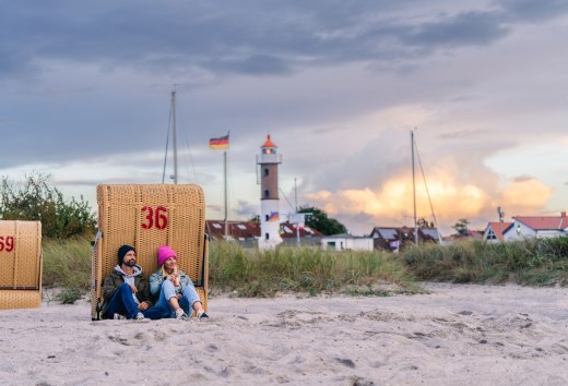 Paar zittend in een strandstoel op het strand in Timmendorf op Poel met uitzicht op de vuurtoren en de avondlucht.