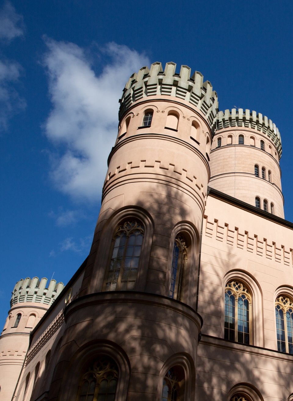 Granitz hunting lodge on Rügen with round towers and battlements against a blue sky. // Close-up of the magnificent Granitz hunting lodge on the island of Rügen. The round towers with their striking battlements rise up against a bright blue sky. The sunlight casts light shadows on the sand-colored facades and ornate windows. // © MV-T/Prast Granitz hunting lodge on Rügen with round towers and battlements against a blue sky.
