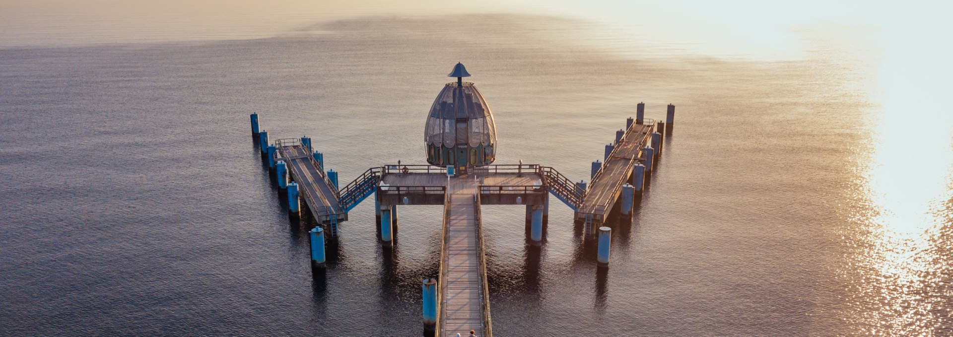 Drone-opname van de duikgondel bij de pier van Sellin, met houten steiger en de Baltische Zee in het gouden licht van een zonsondergang.