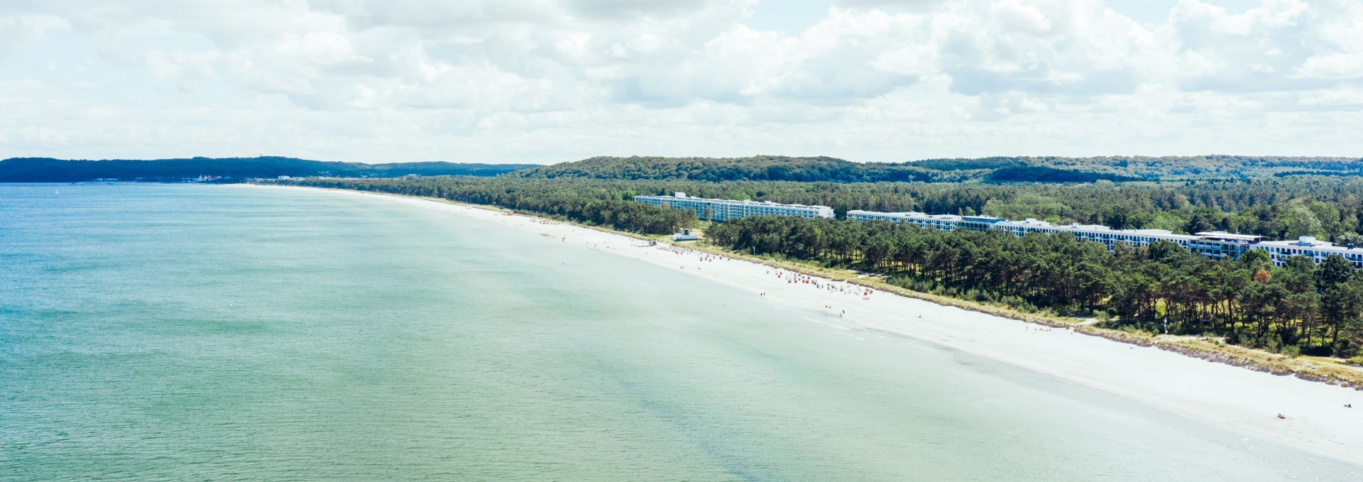 Luchtfoto van de lange zandstranden van Prora op Rügen met het historische gebouwencomplex en het aangrenzende kustbos.