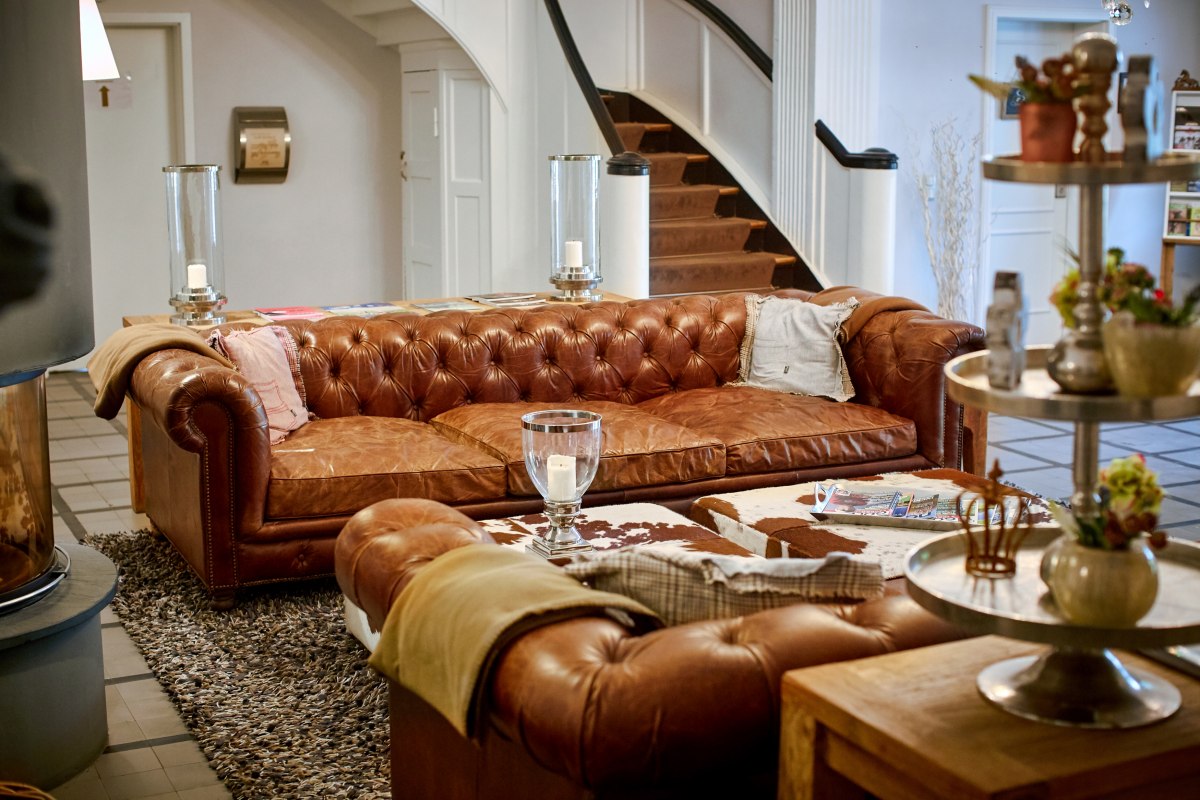 Zapraszający hol z kominkiem i przytulnymi sofami w Gut Vorbeck // &copy; Gut Vorbeck / Thomas Mandt