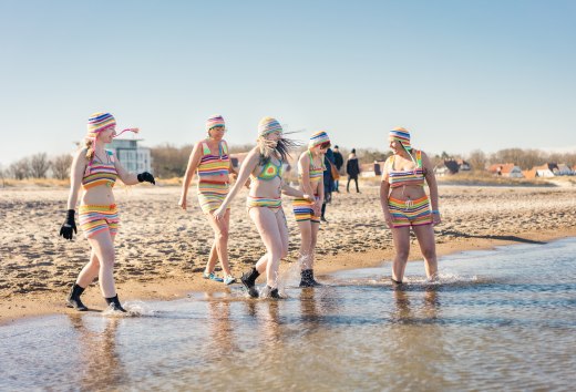IJsbaders nemen een duik in de Baltische Zee op het strand van Warnemünde in de zon.