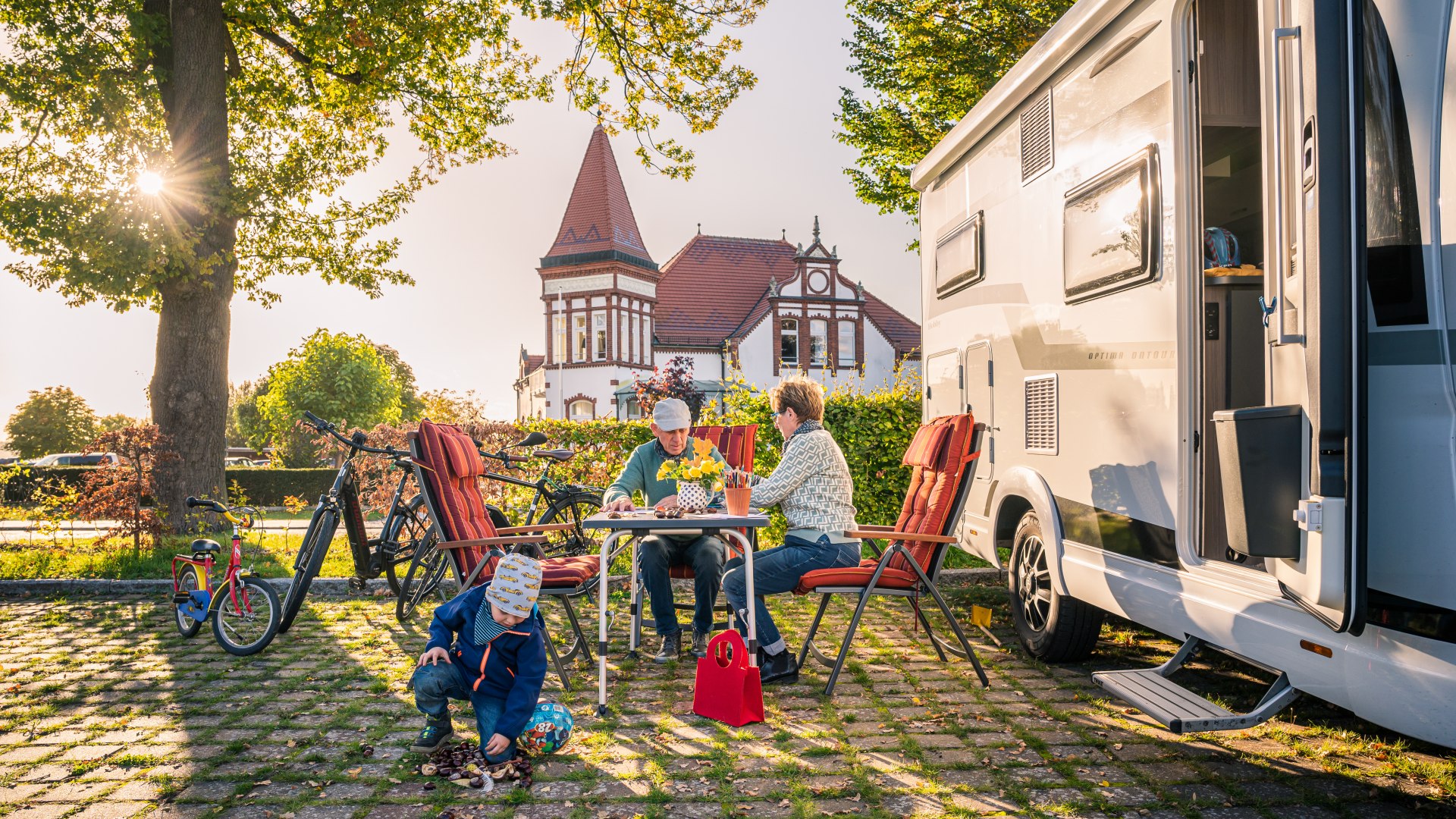 Oma, opa en kleinkinderen voor de camper op de kampeerplaats bij de stadshaven in Neustrelitz bij zonsondergang