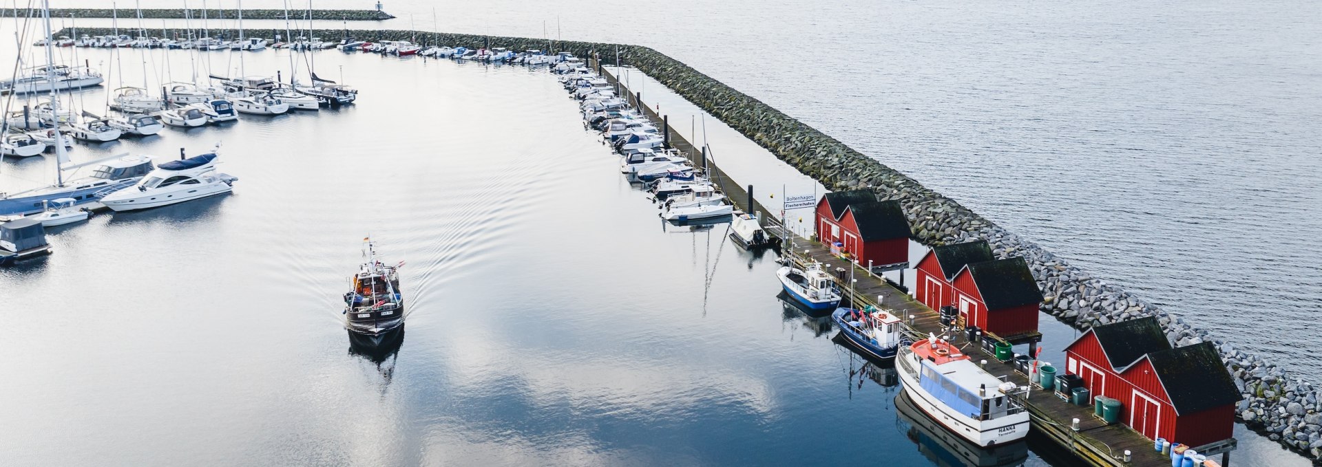Als je de vissershaven van Boltenhagen verlaat, passeer je de iconische rode vissersschuren, die prachtig weerspiegeld worden in het gladde water van de havenkom., © TMV/Gross