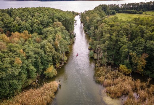 Een kano peddelt door een klein kanaal van het ene meer naar het andere.