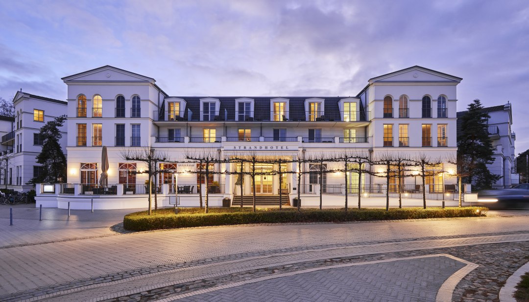 Illuminated Strandhotel Zingst in the style of spa architecture at dusk, taken from the street side.