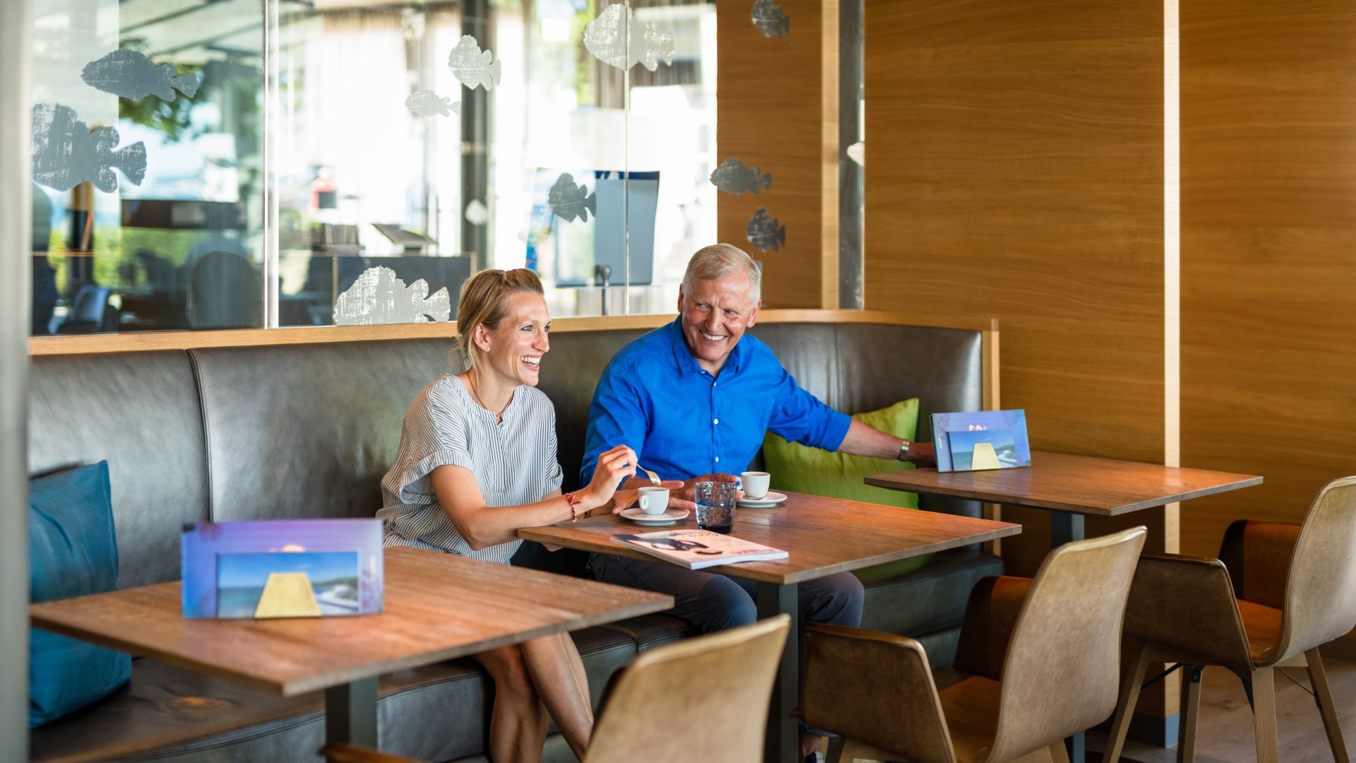 Lang aan boord: Wolfgang Schewe met dochter Johanna in het restaurant van Hotel am Meer, © TMV/Tiemann Wolfgang Schewe met zijn dochter Johanna in het restaurant van Hotel am Meer met een kopje koffie en allebei lachend.