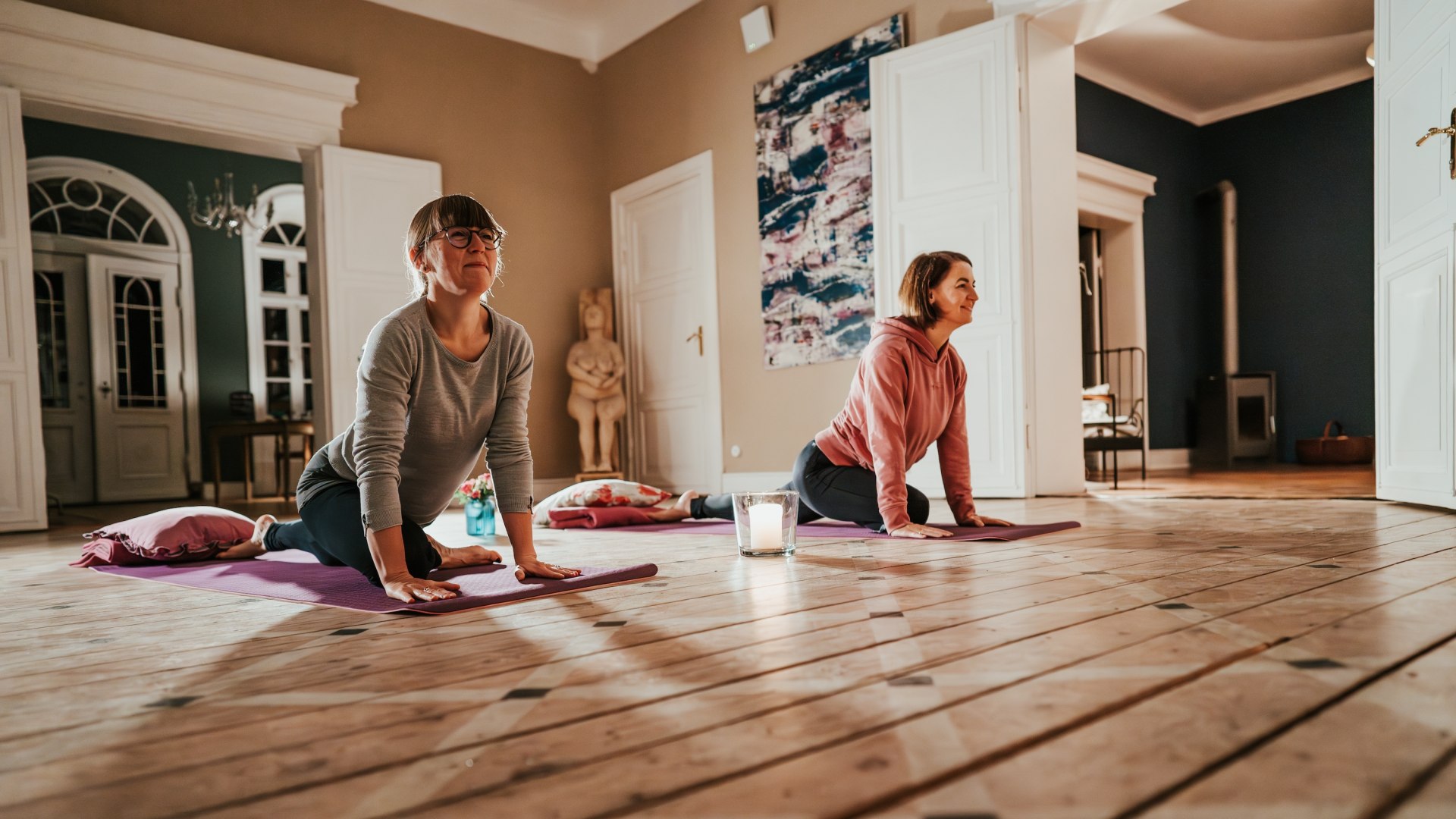 Twee deelnemers genieten van een yogasessie in Gutshaus Pohnstorf - mindfulness en beweging in een stijlvolle en ontspannen omgeving., © 1000seen.de Twee deelnemers genieten van een yogasessie in Gutshaus Pohnstorf - mindfulness en beweging in een stijlvolle en ontspannen omgeving.