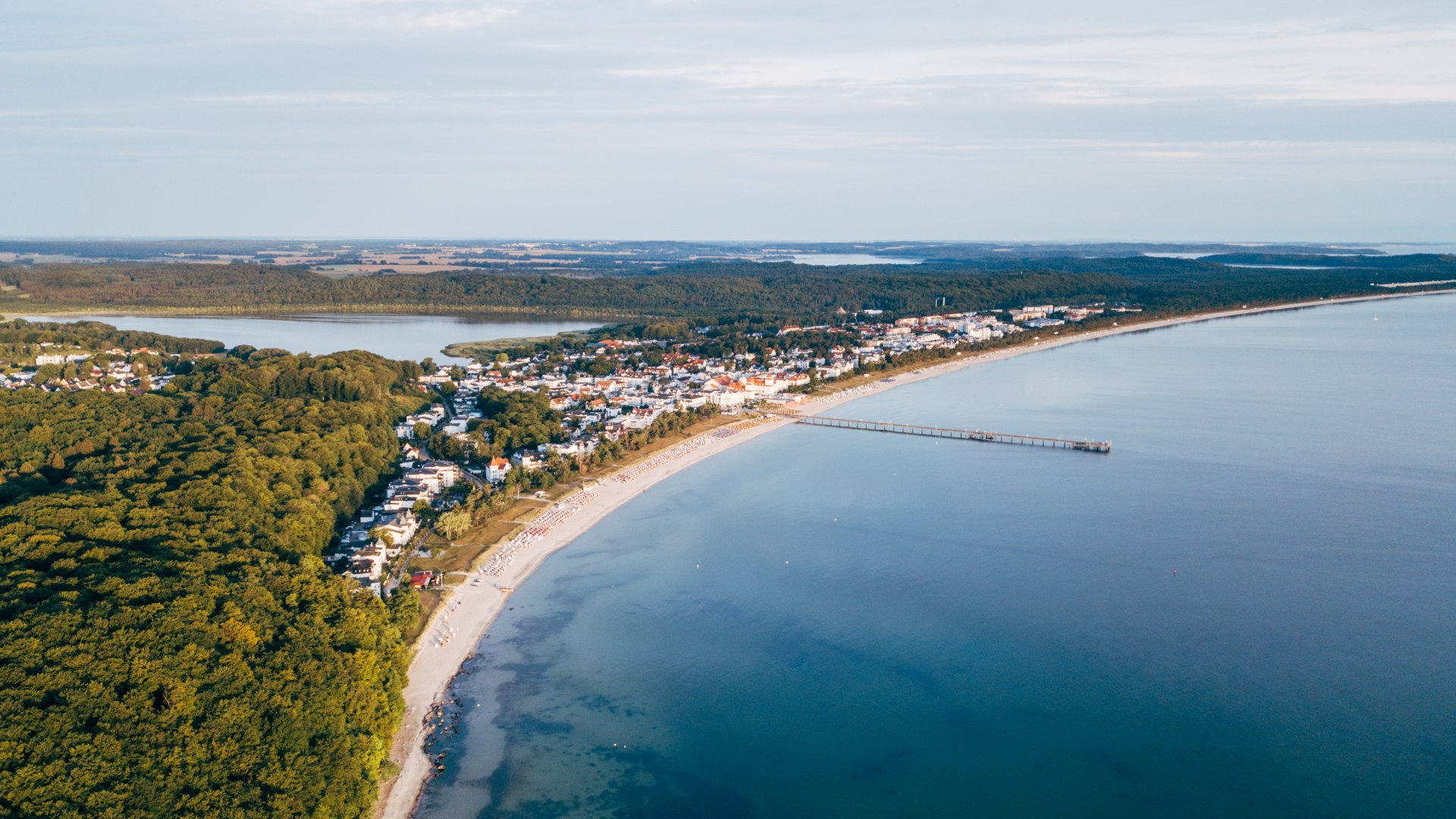 The beach and promenade of Binz from the air with the pier and part of the Baltic Sea at sunrise