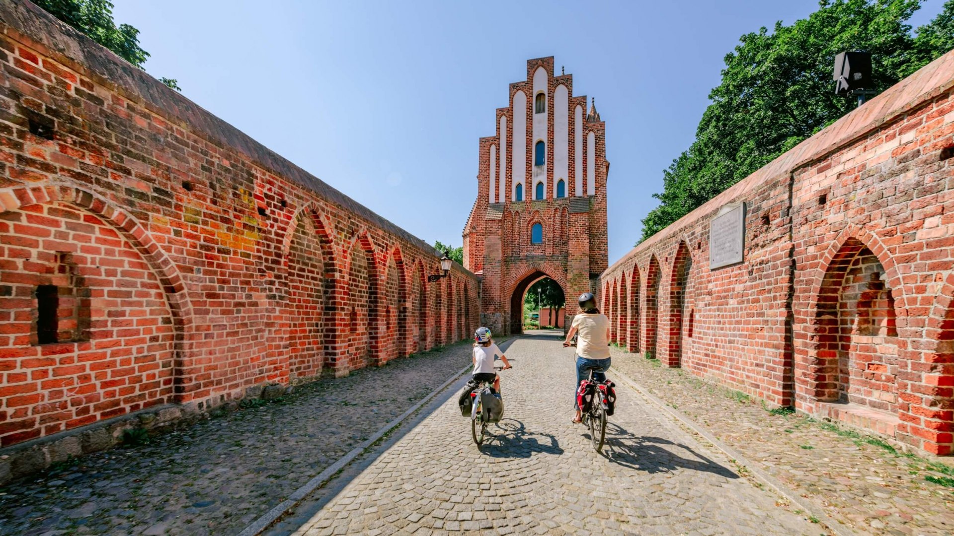 Matka z dzieckiem przejeżdżają przez Friedländer Tor w Neubrandenburgu.