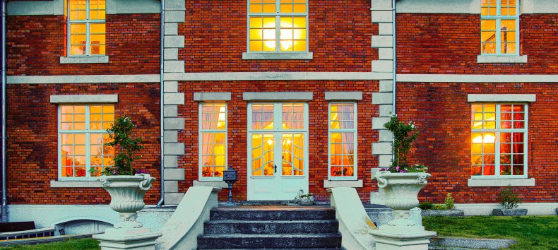 Illuminierter Eingang des Herrenhauses Brookhusen: Historistische Backsteinfassade und einladend leuchtende Fenster in der Abenddämmerung. // © Herrenhaus Brockhusen Illuminierter Eingang des Herrenhauses Brookhusen: Historistische Backsteinfassade und einladend leuchtende Fenster in der Abenddämmerung. // © Herrenhaus Brockhusen
