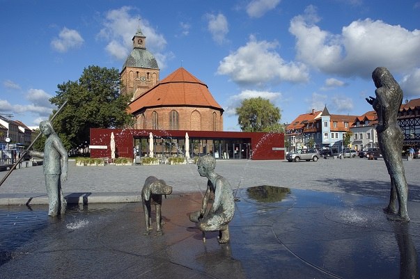 Ribnitz marktplein met fontein "The Amber Fisherman" van Thomas Jastram, op de achtergrond Amberhuis met toeristeninformatiecentrum en St. Mary's kerk, © Stadt RDG, Amt für Tourismus, Schule und Kultur