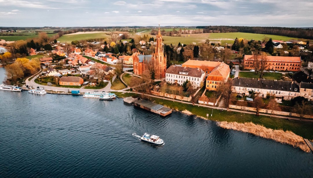 Aerial view with red church and boats on the shore of Lake Malchow in Mecklenburg-Western Pomerania.