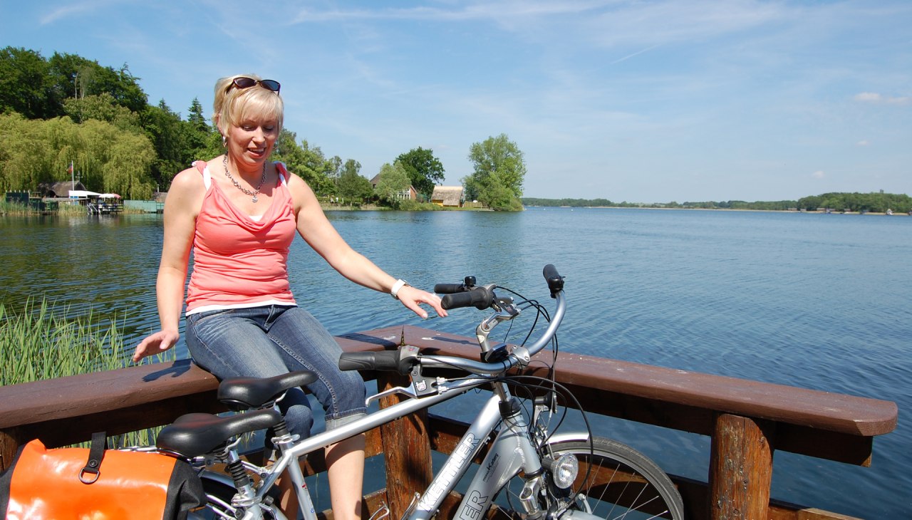 Een fietser zit op een reling bij het meer., © Ralf Tetmeyer, radreisen-mecklenburg Een fietser zit op een reling bij het meer., © Ralf Tetmeyer, radreisen-mecklenburg