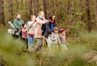 Kinder und Erwachsen genießen gerade ein Waldbad. Sie gehen achtsam und mit geschlossenen Augen durch einen Wald. // © Dominic Mann tiefen-blick.de Kinder und Erwachsen genießen gerade ein Waldbad. Sie gehen achtsam und mit geschlossenen Augen durch einen Wald. // © Dominic Mann tiefen-blick.de