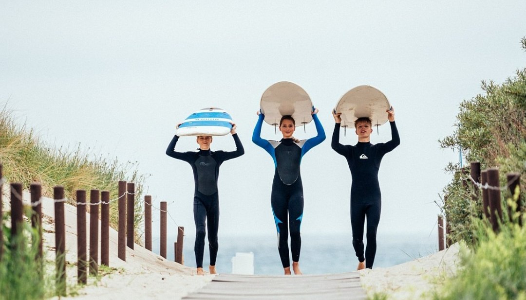 Teilnehmer der Surfcamps kommen den Strandaufgang mit ihren Surfboards hoch. // © MV-T/Felix Gänsicke Teilnehmer der Surfcamps kommen den Strandaufgang mit ihren Surfboards hoch. // © MV-T/Felix Gänsicke