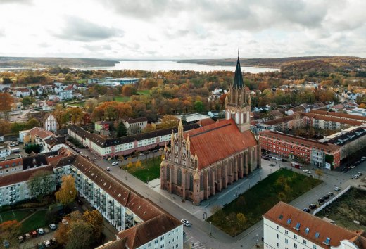 Widok na stare centrum miasta Neubrandenburg z kościołem koncertowym i jeziorem Tollensesee w tle.