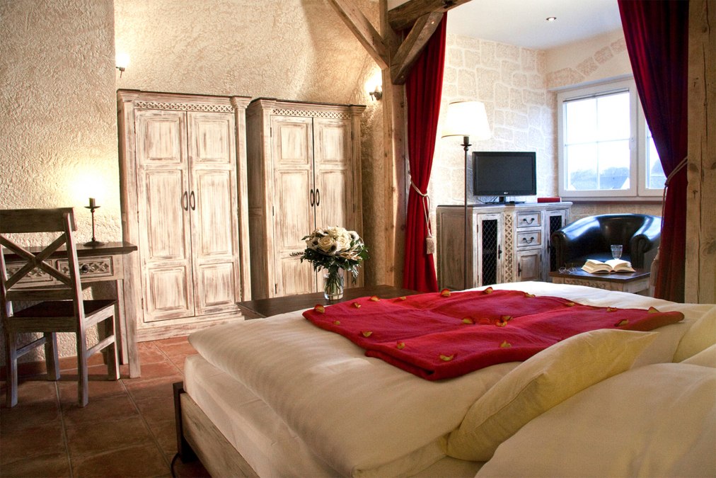 "Kastell GiebelStube Romantik-Traum"(DZ for max. 2 persons, no children)Romantic style:wooden beam bed or gothic metal bed. Bay window with armchairs/sofa.32? / 81cm LED TV with radio. Writing desk.Shower & WC. Cosmetic mirror & hairdryer.About 25 m² in the attic in the house Kastell., © BinzHotel.de/Eigentümer/WAECHTER