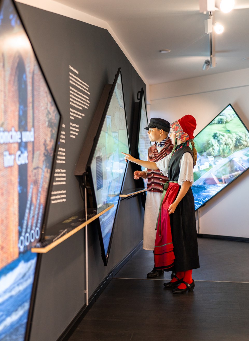 Kinderen staan in het museum in traditionele Mönchgut klederdracht en bekijken de tentoonstelling.