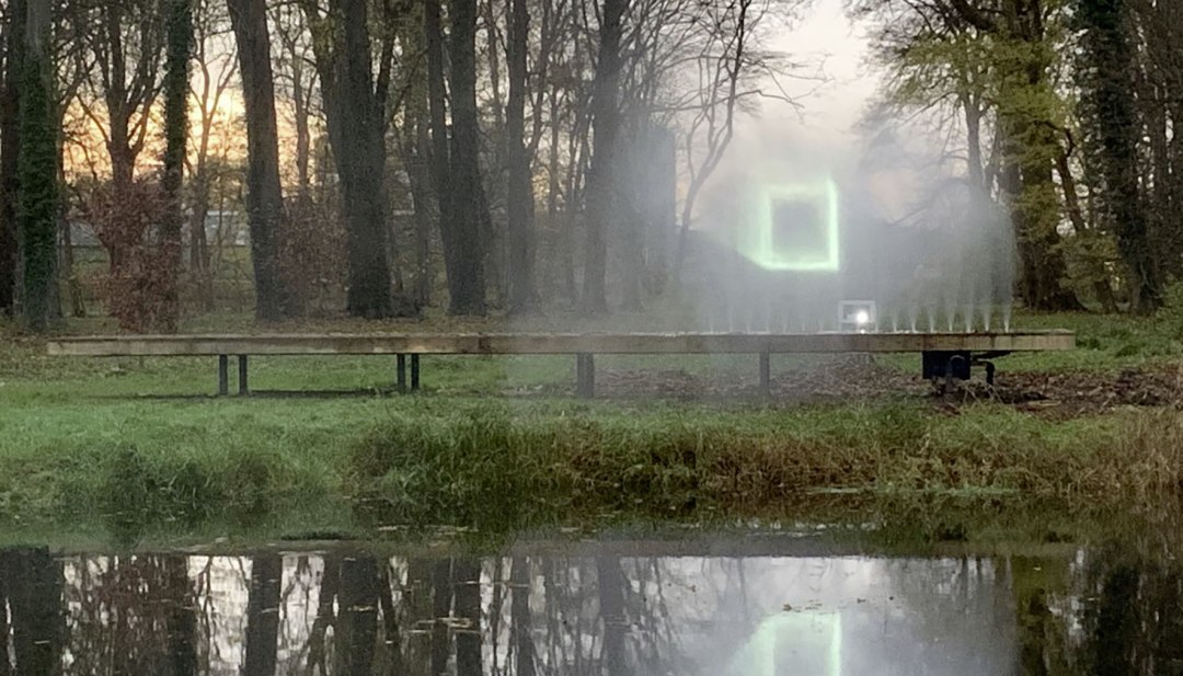 A magical moment at KUNST HEUTE - a luminous projection on water mist enchants the evening atmosphere in the park and is atmospherically reflected in the pond., © Alex Schweder Luminous light installation on water mist in the park with reflection in the pond during the event series KUNST HEUTE.