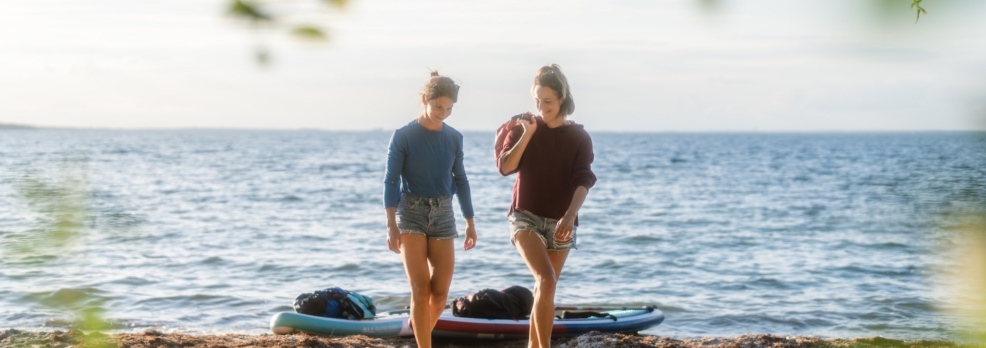 De zon staat al laag als de twee vrienden hun boards aan land trekken op het kleine zandstrand voor de camping Bolter Ufer. Achter hen lijkt de Müritz bijna op de zee., © TMV/Gross