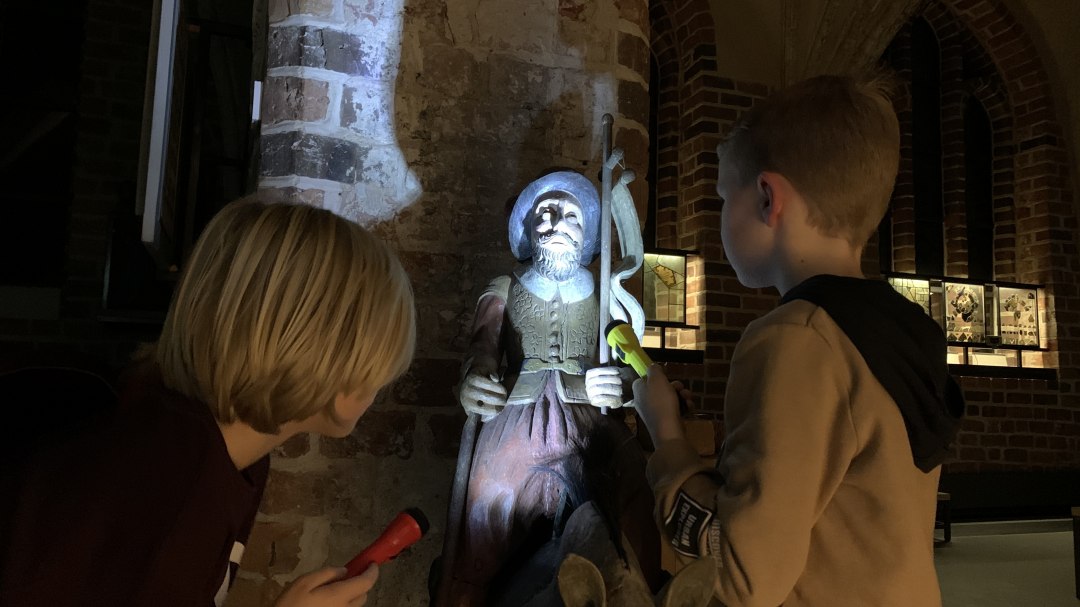 "Kinderen staan met fakkels voor een historisch figuur in het regionale museum. Ze verlichten deze figuur, &copy; Vier-Tore-Stadt Neubrandenburg