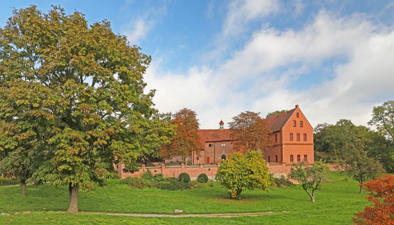 Kasteel Penzlin in Mecklenburg-Vorpommern, bakstenen gebouw met een rood dak, omgeven door park en bomen.