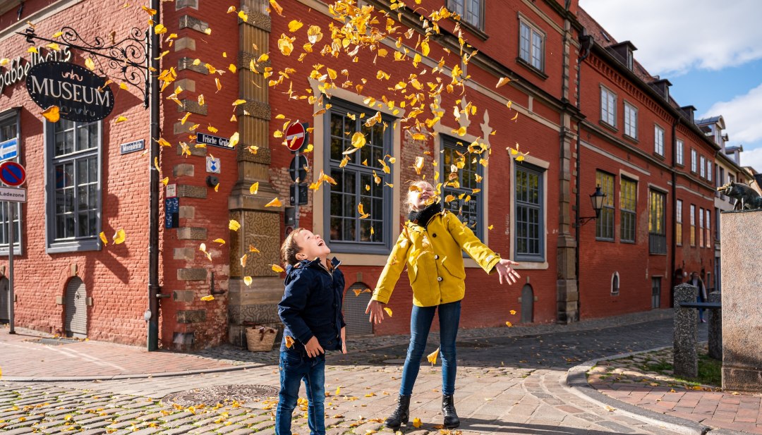 Herfstvakantie aan de Baltische kust van Mecklenburg en kinderen die spelen met herfstbladeren voor het Schabbell Museum.