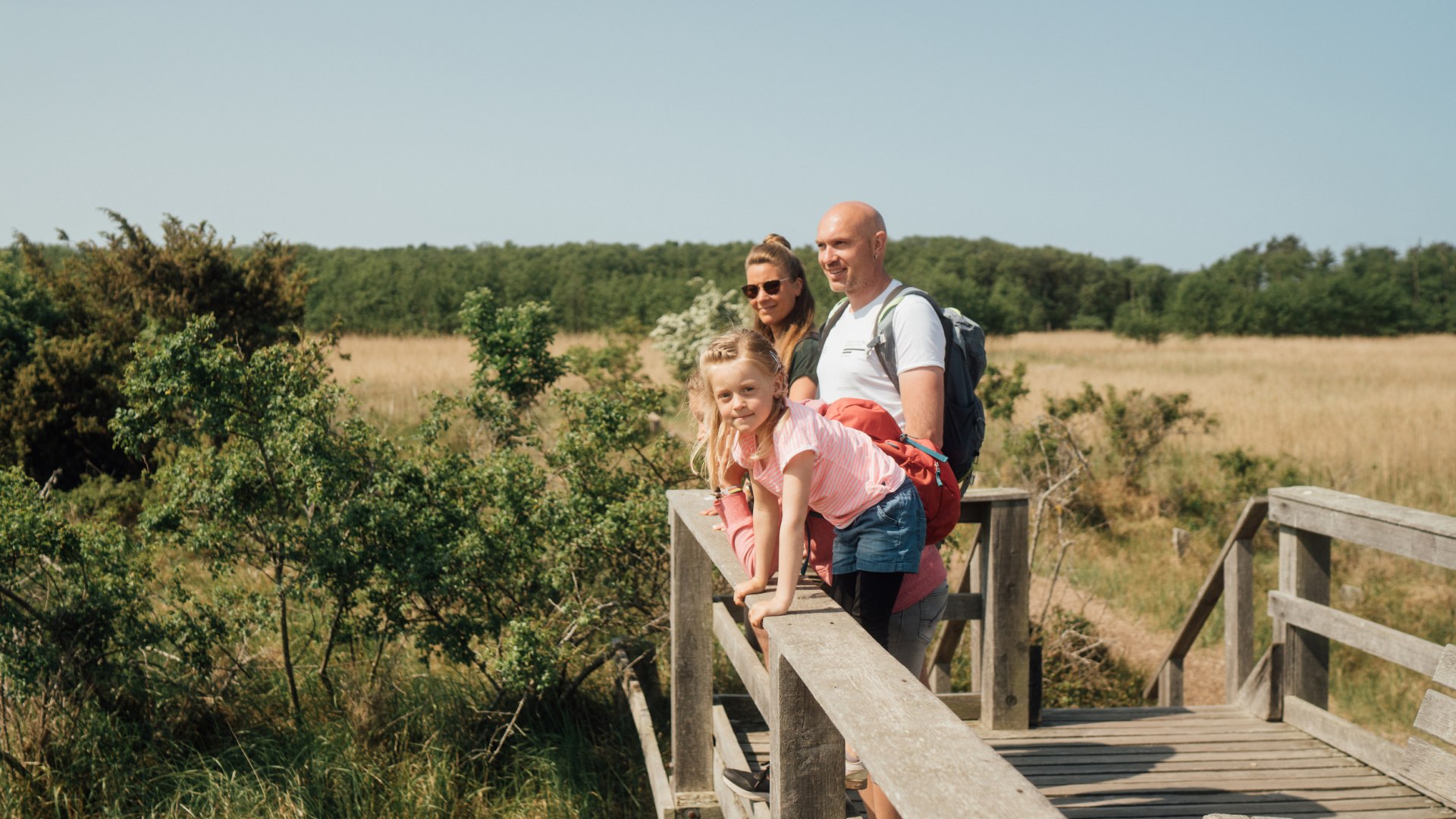 Een gezin staat in de zomer op een uitkijkpunt in het nationale park en kijkt in de verte.
