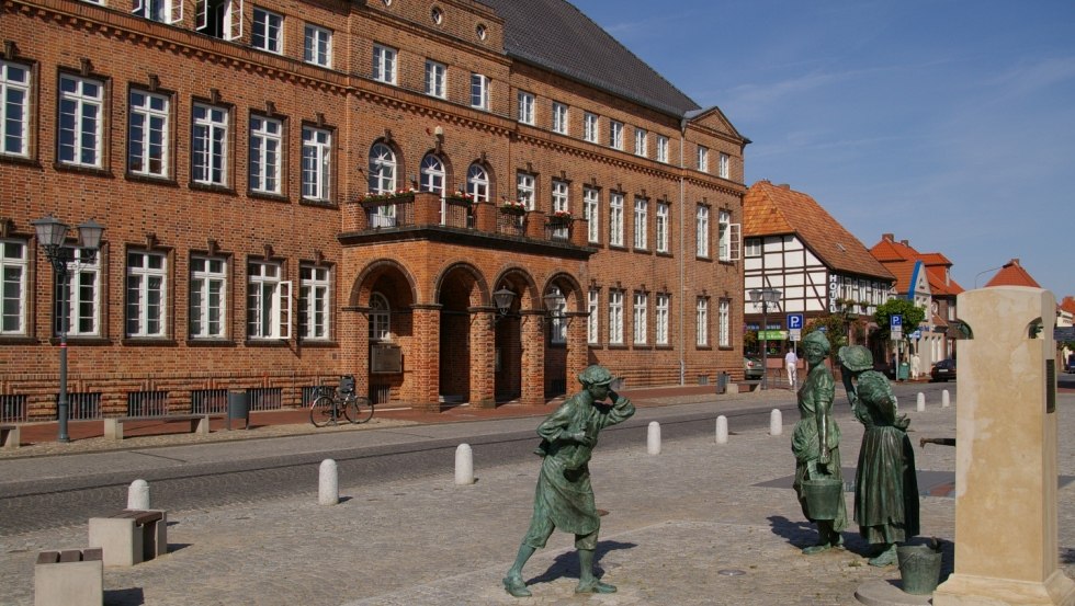 Stadhuis met Fiek`n fontein en grappige groep figuren, © Stadt Hagenow