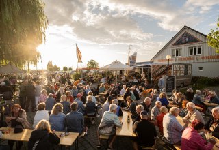 Live-Musik am Ribnitzer Fischhafen: volle Bänke, Gespräche, Fischduft aus der Räucherei – Hafenflair bis in den Abend. // © Ribnitzer Fischhafen / Hugo Scholz-Witzel Live-Musik am Ribnitzer Fischhafen: volle Bänke, Gespräche, Fischduft aus der Räucherei – Hafenflair bis in den Abend. // © Ribnitzer Fischhafen / Hugo Scholz-Witzel