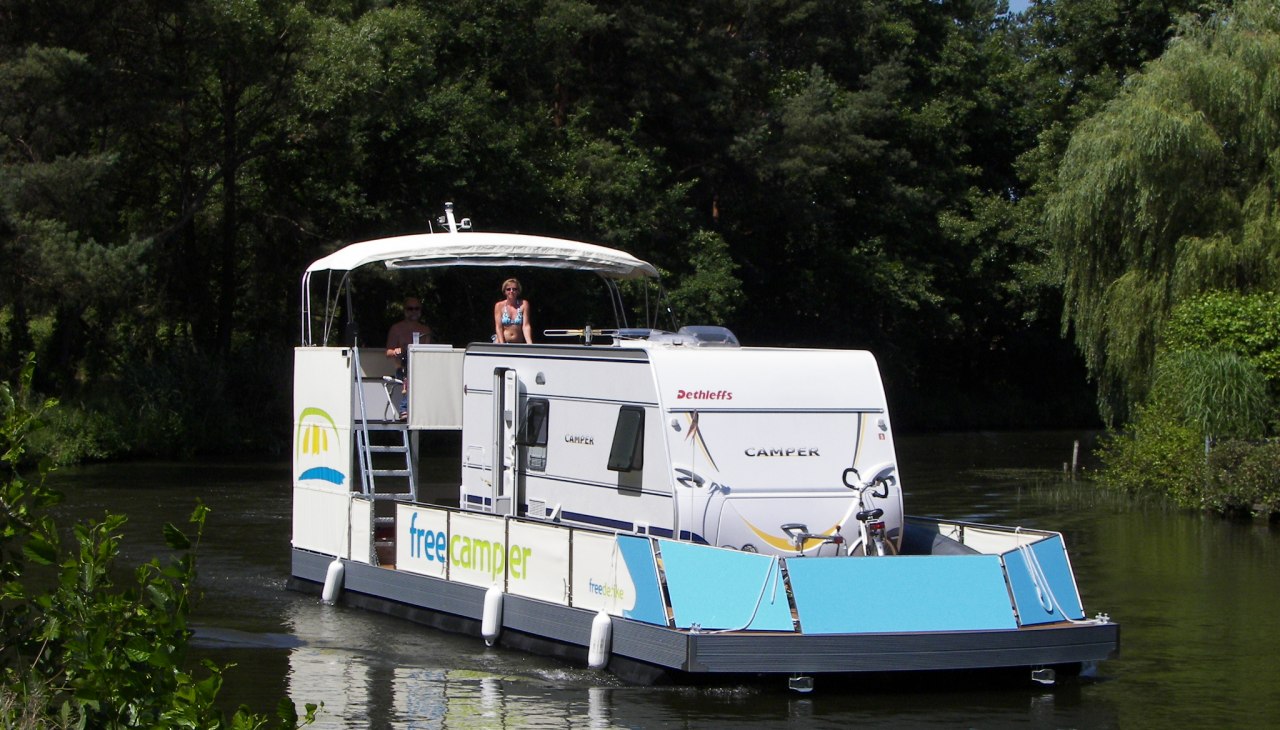 Een camper met caravan slingert door het watergebied van het Mecklenburgse merengebied., © freecamper